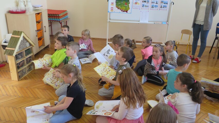 Powiększ: Przedszkolaki oglądają książeczkę "cud miód" oraz domek dla owadów